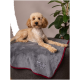 Ein flauschiger, hellbrauner Hund ruht auf einer weichen grauen Decke mit rotem Rand, mit einem gestickten Logo in der Ecke.
