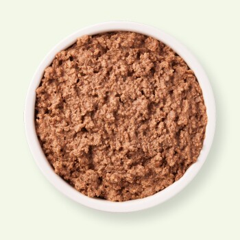 Bol de nourriture pour animaux humide et brune avec une texture en morceaux, sur fond vert clair.