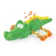 Grünes plüschiges Krokodilspielzeug mit einem lächelnden Gesicht, musikalischen Noten darüber und bunten Seil-Schwänzen.