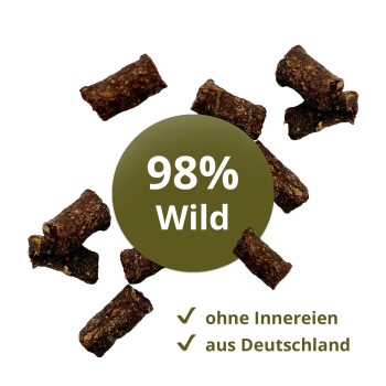 Kleine braune Tierleckerlis um ein grünes Abzeichen '98% Wild' mit Häkchen und den deutschen Phrasen ohne Innereien, aus Deutschland.