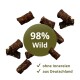 Kleine braune Tierleckerlis um ein grünes Abzeichen '98% Wild' mit Häkchen und den deutschen Phrasen ohne Innereien, aus Deutschland.