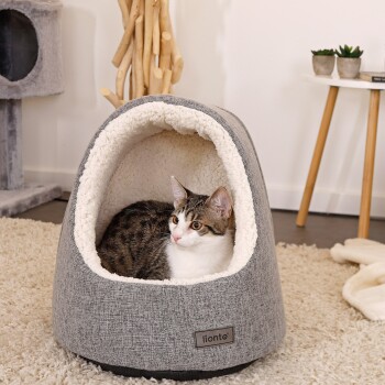 Ein gemütliches graues Katzenbett mit einem flauschigen weißen Innenraum, in dem eine getigerte Katze entspannt. Das Bett hat ein "lionto"-Logo auf der Vorderseite.