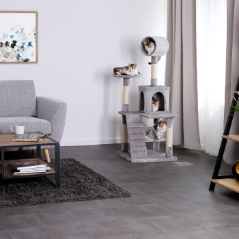 Ein gemütliches Wohnzimmer mit einem grauen Katzenbaum, auf dem drei Katzen faulenzen, einem grauen Sofa, einem Holztisch und einem dekorativen Teppich.