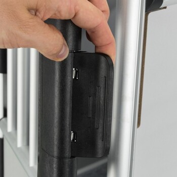 Eine Hand, die einen schwarzen Riegel an einem Haustierzaun anpasst, zeigt den Metallrahmen und die vertikalen Stangen des Zauns.