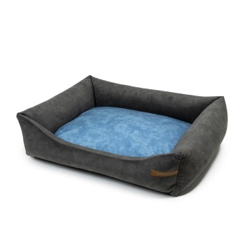 Graues Haustierbett mit einem weichen blauen Kissen, mit erhöhten Seiten für Komfort und einem kleinen Lederetikett an der Seite.