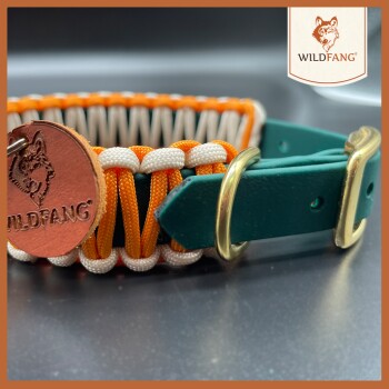 Ein farbenfrohes Hundehalsband mit orangefarbenem, weißem und grünem Paracord-Design und einem Kupferanhänger mit dem "WILDFANG"-Logo.