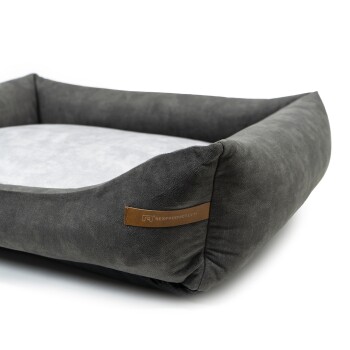 Graues Haustierbett mit einem weichen, hellgrauen Zentrum und erhöhten Rändern, mit einem Lederetikett, das "RexProduct.com" liest.