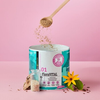 Hund läuft auf Gras mit einer Dose FloraVITAL Tierergänzung, bewirbt natürliche Inhaltsstoffe und Darmgesundheit.