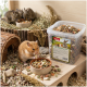 Goldhamster frisst aus einer Schale neben einer PANTO-'Nager Strukturmix'-Dose; im Hintergrund drei Kleinnager auf Heu.