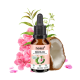 Flasche mit 'noms+ ZPOT-ON' Anti-Zeckenlösung für Katzen, umgeben von rosa Blumen und einer Kokosnuss-Hälfte, mit Text auf dem Etikett.