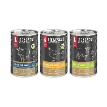 Drei LIEBESGUT-Dosen mit schwarzen Etiketten und Bio-Siegel — 'BIO-RIND FÜR HUNDE', 'BIO-HUHN FÜR HUNDE', 'SCHAF FÜR HUNDE'.
