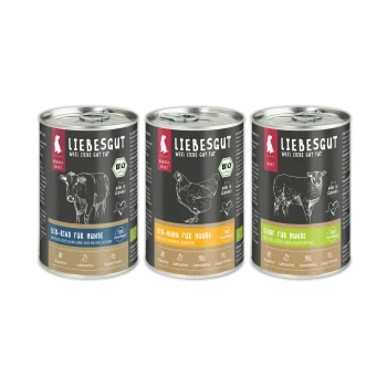 Drei LIEBESGUT-Dosen mit schwarzen Etiketten und Bio-Siegel — 'BIO-RIND FÜR HUNDE', 'BIO-HUHN FÜR HUNDE', 'SCHAF FÜR HUNDE'.