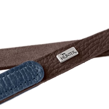 Nahaufnahme eines braunen und blauen Lederhundehalsbands mit einem silbernen "HUNTER"-Logoschild.
