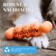 Orangenfarbener, strukturierter Hundekauspielzeug mit Knochensymbolen auf Holz, in der Nähe eines Pfotes. Text: "ROBUST & NACHHALTIG" und "Aus umweltfreundlichem Kautschuk."