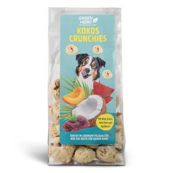 Green Hero Kokos Crunchies, 100 g Hundeleckerli-Verpackung mit "Kokos Crunchies" mit einem Bild eines glücklichen Hundes, Kokosnuss und Früchten; der Text hebt die Zutaten und Qualität hervor.