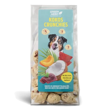 Hundeleckerli-Verpackung mit "Kokos Crunchies" mit einem Bild eines glücklichen Hundes, Kokosnuss und Früchten; der Text hebt die Zutaten und Qualität hervor.