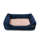 Ein plüschiges, marineblaues Haustierbett mit einem weichen, rosa Innenraum und erhöhten Seiten, mit einem kleinen Holzschild an der Seite.