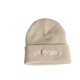 Beige gestrickte Mütze mit umgeschlagenem Saum, mit weißem gesticktem Text, der "HUELSENLIEBE SCHWARZ" liest.