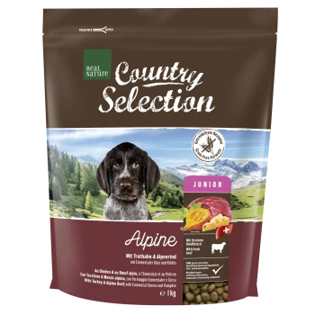 Braune Hundefuttertüte mit einem Hund auf der Vorderseite, beschriftet mit "Real Nature Country Selection Alpine," mit Zutaten, die auf Deutsch und Englisch aufgelistet sind.