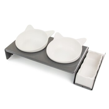 Eine graue Futterstation für Haustiere mit zwei weißen katzenförmigen Schalen und einem kleinen weißen Behälter für Leckerlis oder Utensilien.
