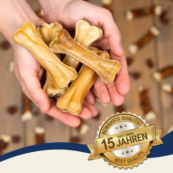 Hände halten hundeknochenförmige Leckerlis mit einem "Beste Qualität"-Abzeichen und "15 Jahre", was über 15 Jahre vertrauenswürdige Qualität anzeigt.