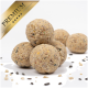 Premium-Haustierfutterbällchen auf einem weißen Hintergrund gestapelt, mit verstreuten Samen um sie herum.