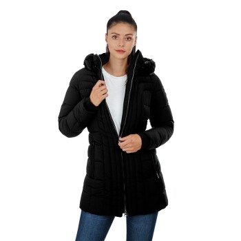 Eine Frau trägt eine schwarze Daunenjacke mit Kapuze, steht mit den Händen am Reißverschluss und ist in einem weißen Shirt und blauen Jeans gekleidet.