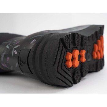 Nahaufnahme der Sohle eines gemusterten Stiefels mit einer schwarzen Basis und floralen Designs sowie orangefarbenen hexagonalen Traktionspads.