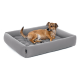 Ein kleiner brauner Hund liegt bequem auf einem grauen rechteckigen Haustierbett mit tufted Design und schaut zur Seite.