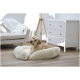 Ein gemütliches, flauschiges Hundebett mit einem hellen Labrador, der darauf ruht, in einem hellen, modernen Wohnzimmer mit einem weißen Sofa und einer Kommode.