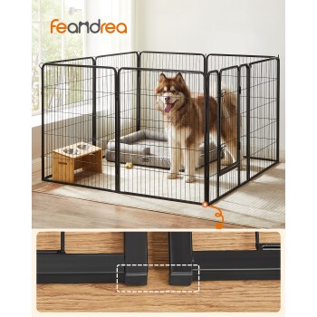 Ein glücklicher, flauschiger Hund steht in einem schwarzen Metallspielbereich für Haustiere mit einem weichen Bett und Futternäpfen in einem hellen Raum. Feandrea-Logo sichtbar.