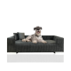 Ein gemütliches dunkelgraues Haustiersofa, auf dem ein Hund bequem liegt, mit zwei dekorativen Kissen auf einer Seite.
