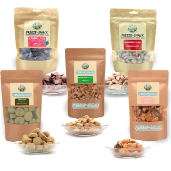 Freeze-Snacks für Hunde als Sparset Verschiedene gefriergetrocknete Haustiersnacks in verschiedenen Verpackungen, darunter Lammlungen, Hühnerherzen und Insektenleckereien, auf Tellern präsentiert.