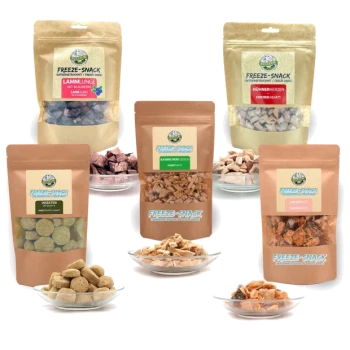 Verschiedene gefriergetrocknete Haustiersnacks in verschiedenen Verpackungen, darunter Lammlungen, Hühnerherzen und Insektenleckereien, auf Tellern präsentiert.