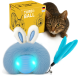 Ein blauer, flauschiger Spielzeug, das einem Hasen ähnelt, mit leuchtenden Augen und angehängten Federn, neben einer gelben Box mit der Aufschrift "Turbo Ball", entwickelt in Deutschland.