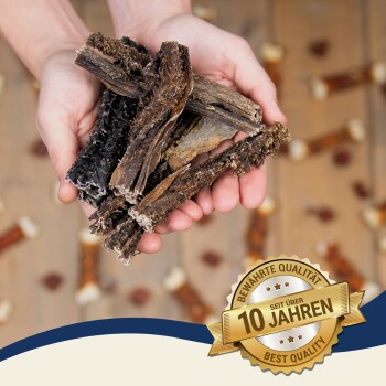 Eine Person hält natürliche Hundekauartikel aus Holz, mit einem goldenen Abzeichen, das "Beste Qualität - seit über 10 Jahren" in der Ecke liest.