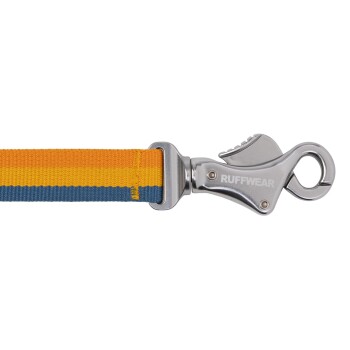 Eine Nahaufnahme einer bunten Hundeleine mit orangefarbenen, gelben und blauen Streifen, mit einem silbernen Metallclip mit der Aufschrift 'RUFFWEAR.'