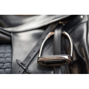 Nahaufnahme eines schwarzen Ledersattels mit einem glänzenden Metallsteigbügel, der mit "EQUINATE" beschriftet ist, und detaillierter Naht und Riemen zeigt.