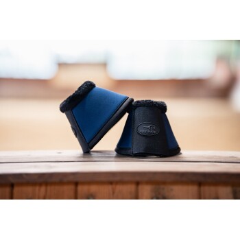 Zwei Pferdeboots in Marineblau und Schwarz, mit einem weichen Fleece-Futter und einem "Equinate"-Logo, auf einer Holzoberfläche präsentiert.