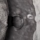 Nahaufnahme eines weichen grauen Haustierbettes mit einem Metallring, der an einem schwarzen Riemen befestigt ist, mit einem kleinen weißen Knoten in der Nähe.