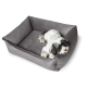 Ein kleiner, flauschiger schwarz-weißer Hund ruht sich bequem in einem grauen Haustierbett mit erhöhten Rändern aus, das ein weiches, plüschiges Innenleben zeigt.