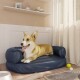 Ein entspannter Corgi liegt auf einem blauen Hundebett in einem gemütlichen Raum, mit einer Hundenapf, Spielzeug und weichen Vorhängen im Hintergrund.