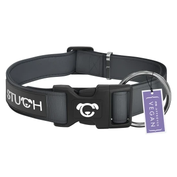 Ein graues Hundehalsband mit einer schwarzen Schnalle, mit dem Wort "STUCH" in Weiß und einem runden Hundelogo. Es hat ein Etikett mit der Aufschrift "PETA APPROVED VEGAN."
