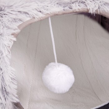Eine gemütliche Haustierhöhle mit weichem, flauschigem Innenraum und einem hängenden weißen Pom-Pom-Spielzeug für verspielte Haustiere.