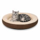 Silbergetigerte Katze mit grünen Augen liegt auf einem runden braun-cremefarbenen Plüsch-Tierbett und blickt in die Kamera.