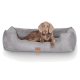 Ein brauner Hund, der bequem in einem weichen, grauen Haustierbett mit einem Lederetikett ruht, das ein gemütliches und stilvolles Design zeigt.