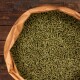 Eine Nahaufnahme eines großen Beutels mit grünen Haustierfutterpellets, vor einem Holz-Hintergrund.