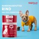 Bild von "Supravit Rind" Hundefutterdosen mit Text über Qualität, Vitamine und getreidefrei. Ein brauner Hund mit geneigtem Kopf ist im Vordergrund.