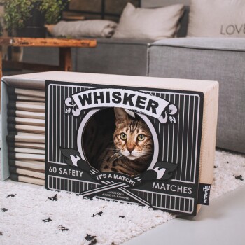 Ein stilvoller Kratzbaum für Katzen, der wie eine Streichholzschachtel aussieht, mit der Aufschrift 'WHISKER' und dem Text '60 SAFETY MATCHES' und 'IT'S A MATCH.'