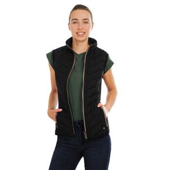 Eine Frau trägt eine schwarze gesteppte Weste über einem grünen Shirt, steht mit den Händen in den Hüften und zeigt einen stilvollen, lässigen Look.